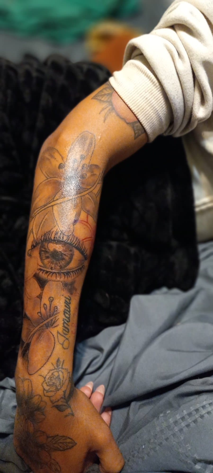 Forearm suite with a lily, a realistic eye, script lettering, and roses running onto the hand