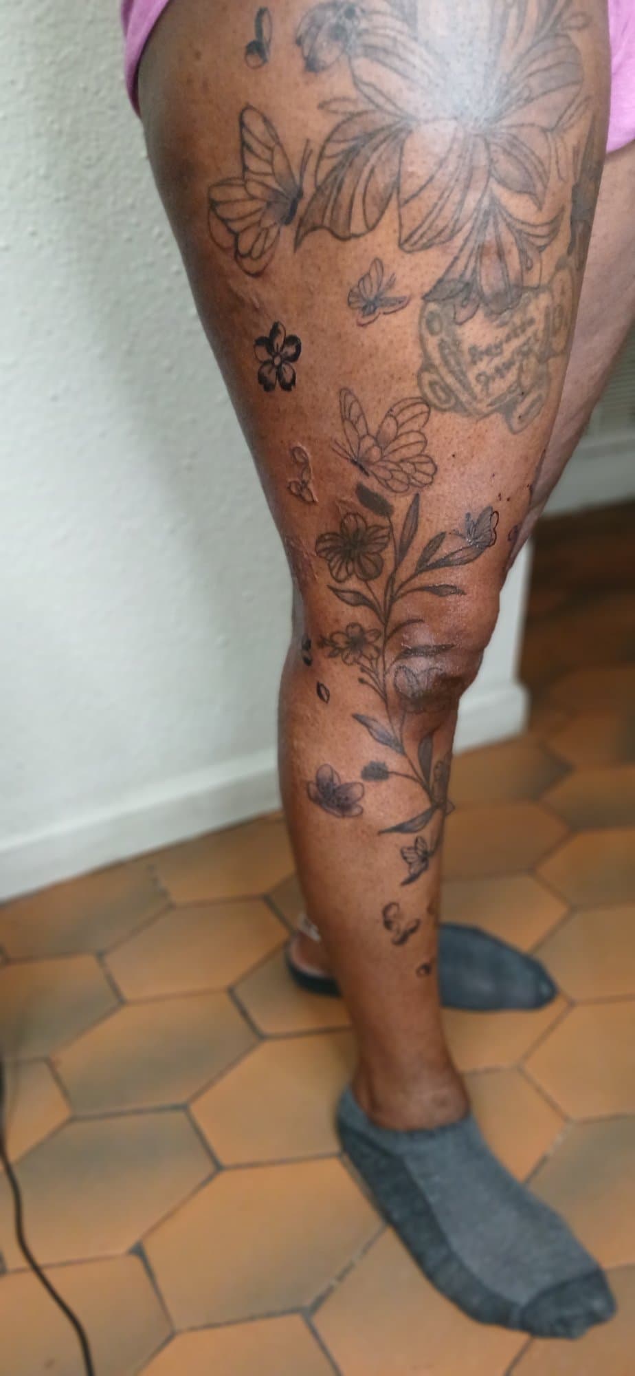 Leg tattoo of butterflies and wildflowers running from thigh to shin